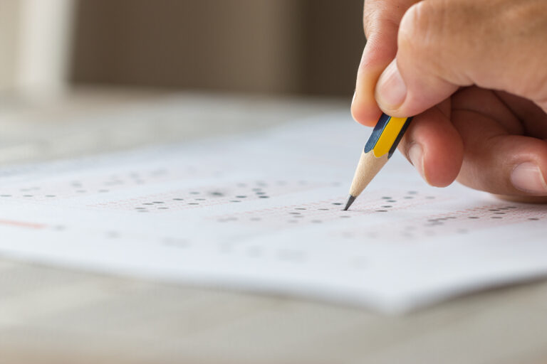 Student writing in an exam hall, representing the NEET PG 2026 exam